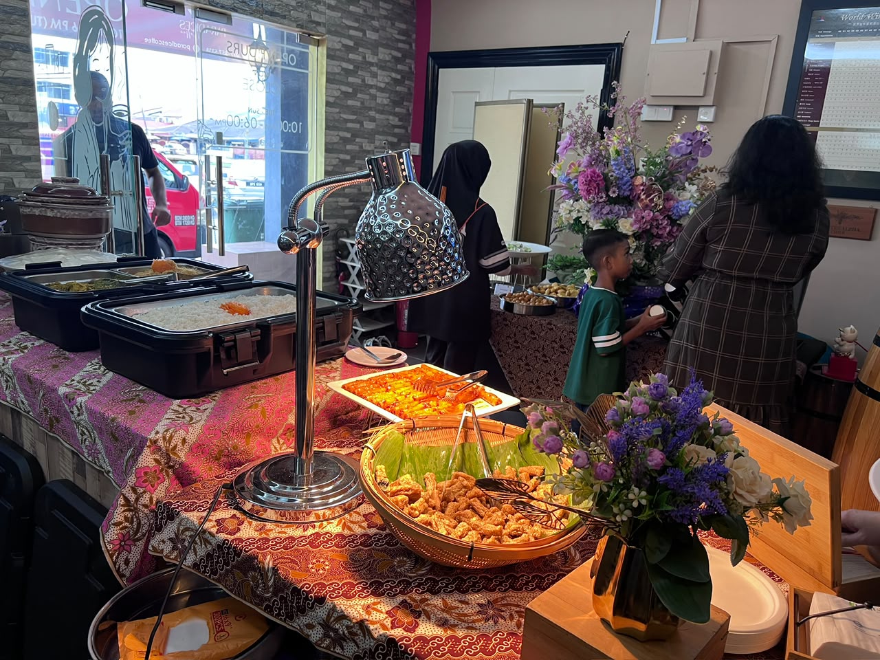 Hari Raya buffet spread on batik table linen with florals and a heat lamp